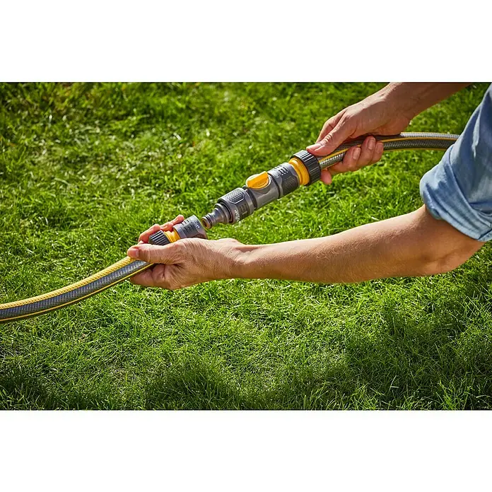 Neptun Regulierventil - ½″ - Eine Person verbindet ein Schlauchstück mit einem Gardena-Wasserstopp-System auf grünem Gras, um die Gartenarbeit zu erleichtern.