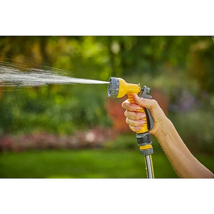 Neptun Brausen-Set - 4 -tlg. - Nahaufnahme einer Hand, die einen gelben Gartenschlauch mit Sprühdüse hält, der Wasser verspritzt, vor einem verschwommenen Gartenhintergrund.