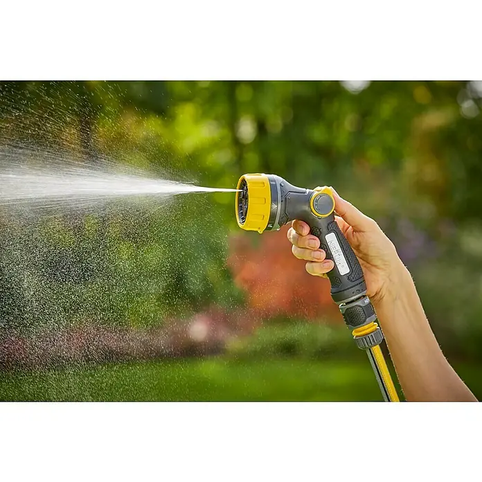 Neptun Bewässerungsbrause - Anzahl Sprühformen: 7 Stk. - Nahaufnahme einer Hand, die einen gelb-grauen Gartenschlauch mit Sprühdüse hält, der Wasser versprüht, mit unscharfem Gartenhintergrund.