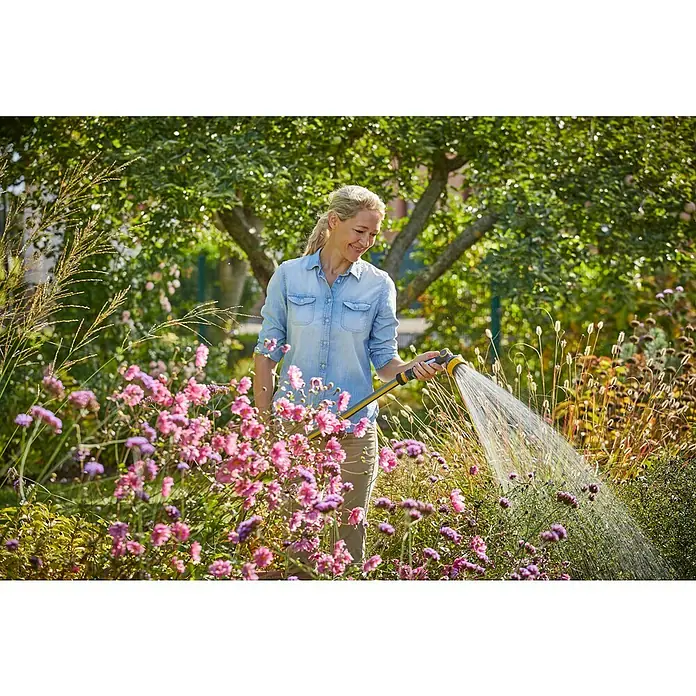 Neptun Bewässerungsbrause - Anzahl Sprühformen: 7 Stk. - Frau gießt Blumen mit einem gelben Gartenschlauch in einem blühenden Garten.