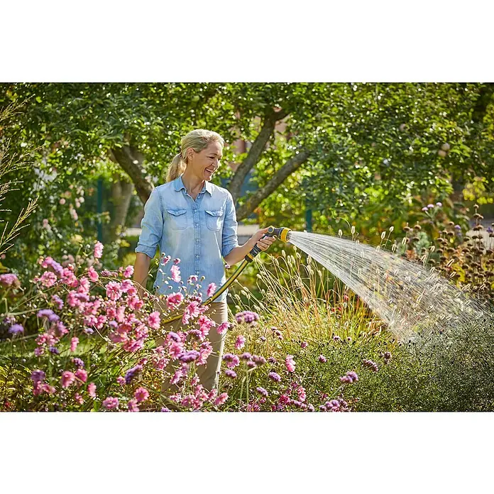 Neptun Bewässerungsbrause - Anzahl Sprühformen: 7 Stk. - Eine Frau gießt mit einem gelben GARDENA-Gartenschlauch ihre Blumen im Garten und erfreut sich an der Gartenarbeit an einem sonnigen Tag.