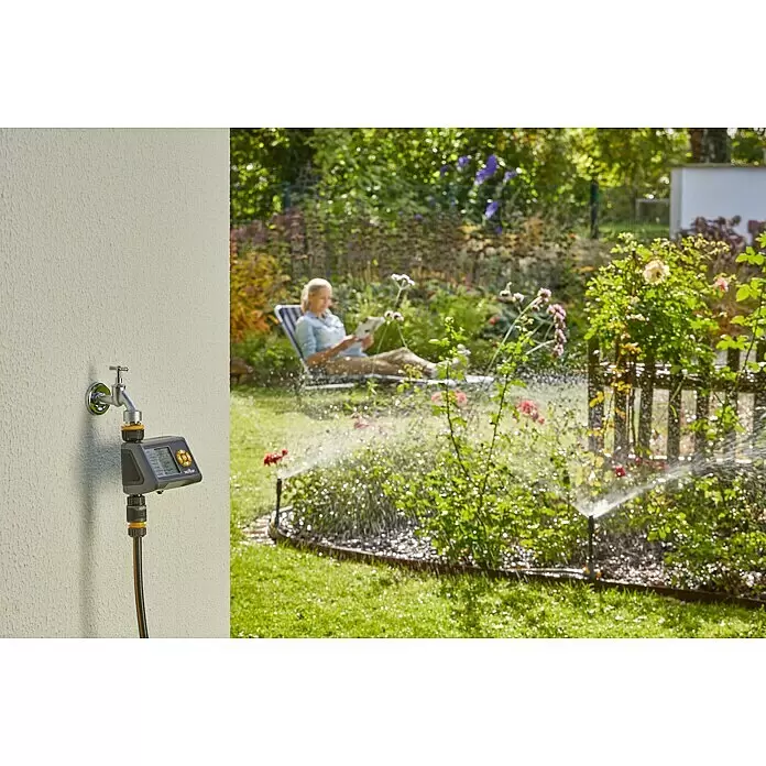 Neptun Kreisregner Set - 7 -tlg., Beregnungssektor: 5 ° - 360 ° - Ein grauer und schwarzer Bewässerungstimer mit gelben Tasten ist an einen Wasserhahn angeschlossen und steuert Gartensprinkler im Hintergrund, wo eine Person entspannt.