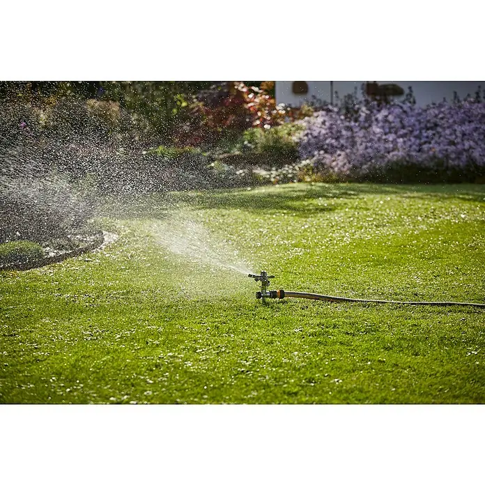 Neptun Sektorenregner - Metall, Max. Regnerfläche: 480 m² - Rasensprenger bewässert den grünen Rasen mit Spritzern, während Blumen im Hintergrund blühen.