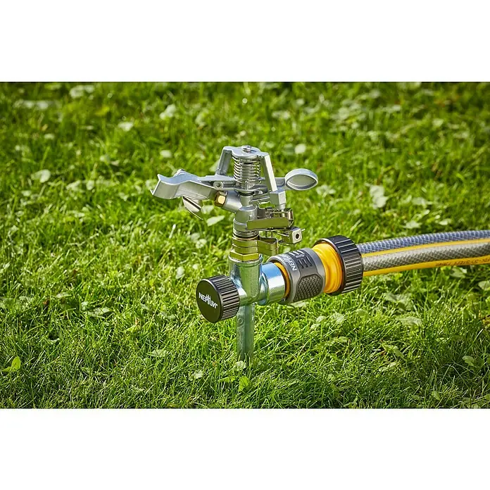 Neptun Sektorenregner - Metall, Max. Regnerfläche: 480 m² - Eine Nahaufnahme eines Rasensprengers, der auf einer grünen Rasenfläche steht und an einen gelben Gartenschlauch angeschlossen ist.
