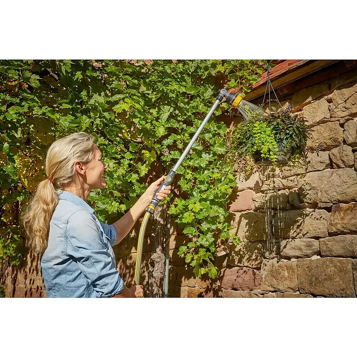 Neptun Gießstab - Länge: 76 cm, Aluminium/Kunststoff - Eine Frau gießt Blumen mit einer GARDENA Lanze, die an einem Schlauch befestigt ist, um schwer erreichbare Stellen zu befeuchten.