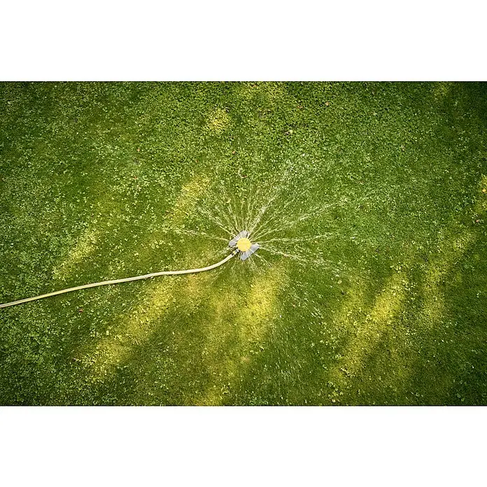 Neptun Vielflächenregner - Kunststoff - Rasensprenger bewässert einen grünen Rasen mit gelbem Schlauch, der daran befestigt ist, und sorgt für eine gleichmäßige Bewässerung.