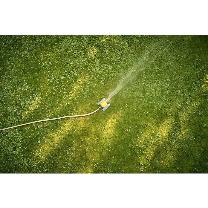 Neptun Vielflächenregner - Kunststoff - Rasensprenger in Aktion. Der gelb-graue Sprinkler bewässert einen grünen Rasen und sorgt für eine saftige Gartenlandschaft.