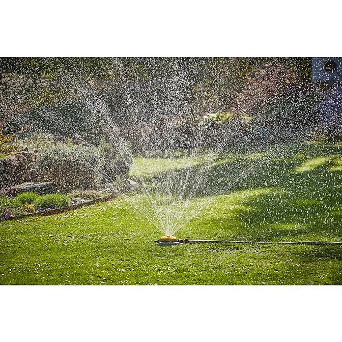 Neptun Vielflächenregner - Kunststoff - Rasensprenger in Aktion: Bewässerung mit einem gelben Sprinkler auf einem grünen Rasen, der von Wasserstrahlen umgeben ist.