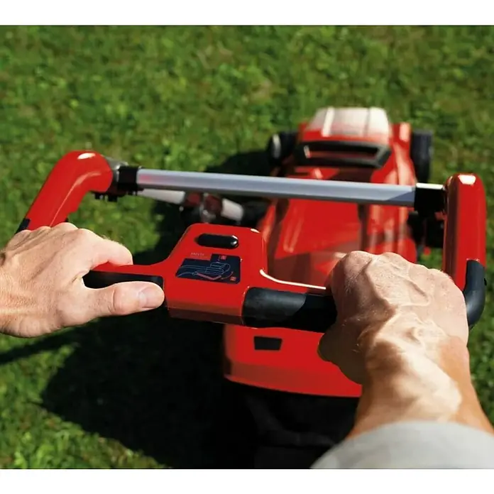 Einhell Power X-Change 18V Akku-Rasenmäher Rasarro 36/36 - 36 V, 2 Akkus, 3 Ah, Schnittbreite: 36 cm - Nahaufnahme eines roten Rasenmähers, der von zwei Händen auf einem grünen Rasen bedient wird.