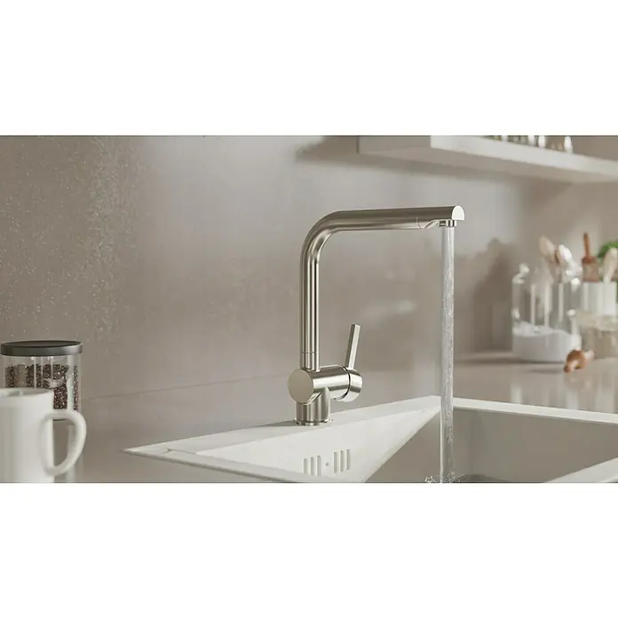 Camargue Spültischarmatur Antea - Edelstahl, Matt - Nahaufnahme einer modernen Küchenarmatur aus Edelstahl, aus der Wasser in ein weißes Spülbecken fließt, minimalistisches Design.