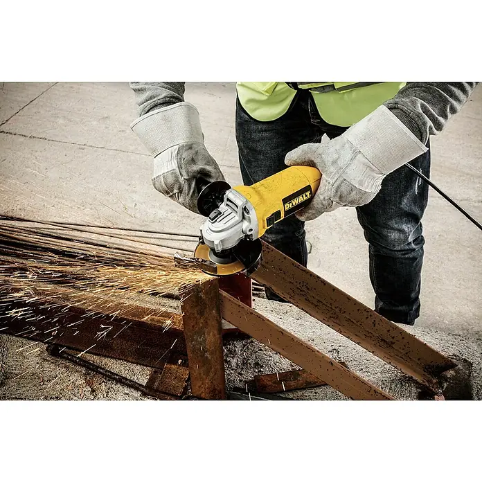 DeWalt Amoladora angular eléctrica DWE4117 - 950 W, Diámetro disco: 125 mm, Número de revoluciones de marcha en vacío: 12.000 r.p.m. - Primer plano de un trabajador de la construcción cortando metal con una amoladora angular amarilla DeWalt, saltando chispas. Ropa protectora bien visible.