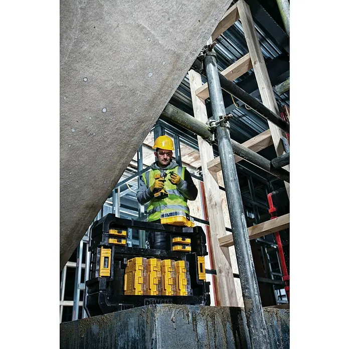 DeWalt Werkzeugkasten - Kunststoff, L x B x H: 437 x 310 x 120 mm - Ein Bauarbeiter mit Schutzhelm und Dewalt Werkzeugkoffer auf einer Baustelle.