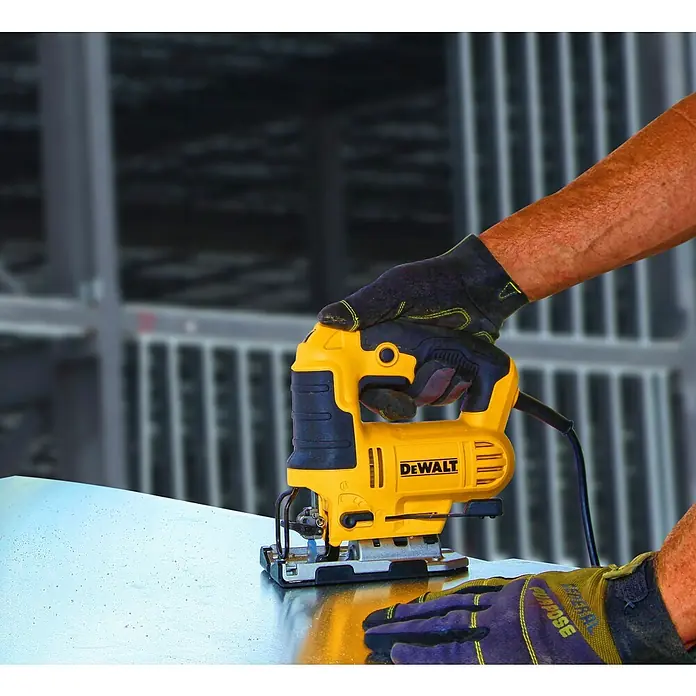 DeWalt Elektro-Pendelhubstichsäge DWE349-QS - 500 /min - 3.200 /min, Max. Schnitttiefe in Holz: 85 mm, Anzahl Pendelhubstufen: 3 Stk. - Nahaufnahme einer gelben DEWALT Stichsäge in Aktion, bedient von einer Person mit Handschuhen, die ein Metallstück schneidet.