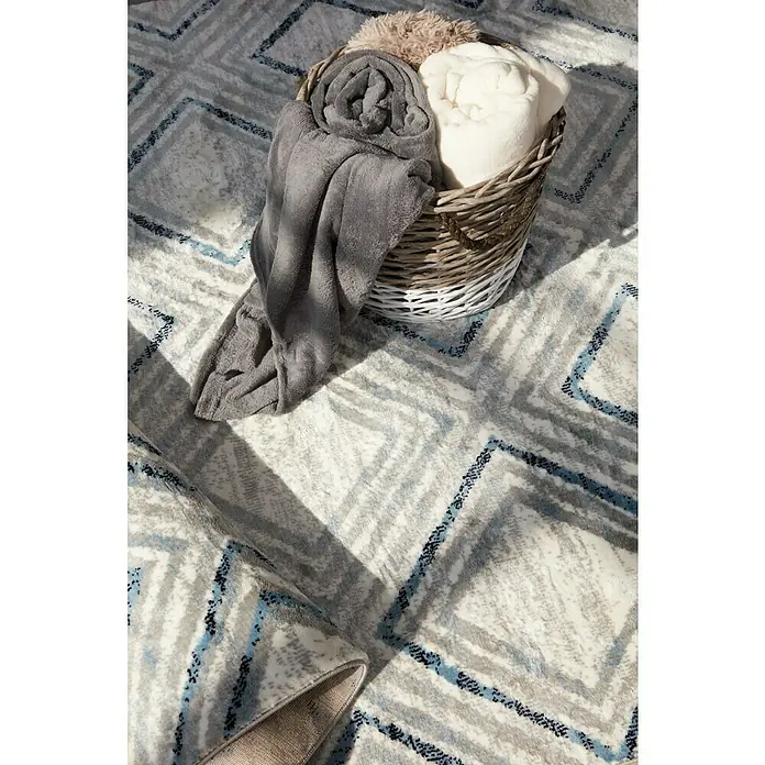 Manta para sofá Luxury - Multicolor - Dispuesto con arte: una cesta acogedora con mantas suaves sobre una elegante alfombra con patrón geométrico.