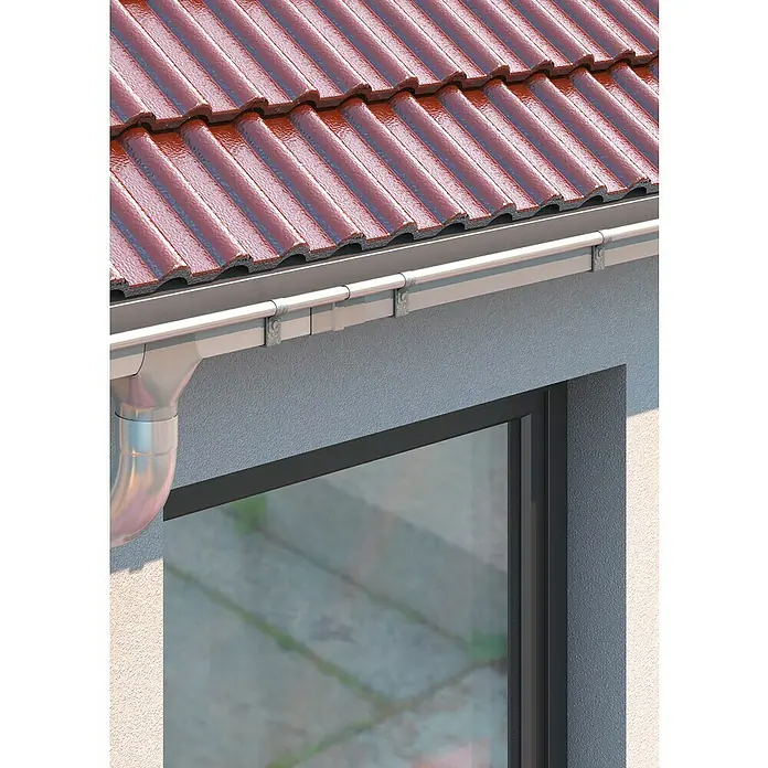 Sarei Kastenrinnenverbinder - Nennweite: 70 mm, Aluminium, Silber - Detailaufnahme einer Dachrinne mit rotem Ziegeldach im Hintergrund. Die Rinne ist aus Metall und an einer Hauswand befestigt.