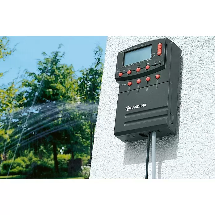 Gardena Sprinklersystem Verbindungskabel 24 V - 15 m - Dunkelgraue GARDENA Bewässerungssteuerung an einer Wand, die einen Rasensprenger im Garten regelt.