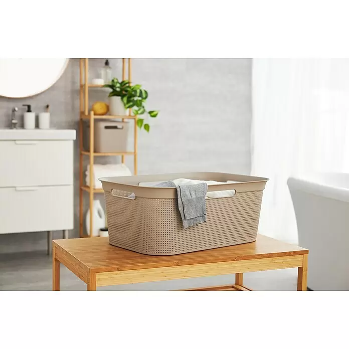 Rotho Wäschekorb Brisen - L x B x H: 59,6 x 39,6 x 23,2 cm, Kunststoff, Cappuccino - Beiger perforierter Wäschekorb aus Kunststoff mit Kleidung auf einer Holzbank im Badezimmer.