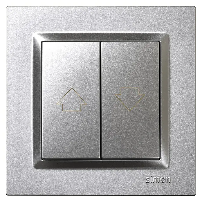 Simon 10 Tecla de control de persiana - Aluminio, Montaje en superficie, 10 A - Primer plano de un interruptor Simon plateado con flechas arriba y abajo, diseñado para controlar persianas o contraventanas, diseño moderno.