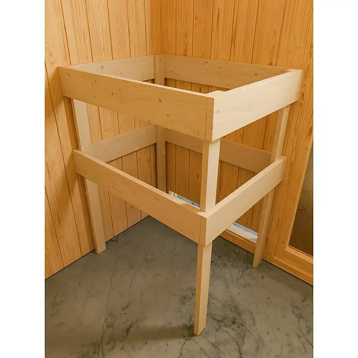 Karibu Elementsauna Nybro - L x B x H: 196 x 231 x 198 cm, Mit 9 kW Saunaofen mit integrierter Steuerung - Eine zweistöckige, unbehandelte Holzkonstruktion, ideal für DIY-Projekte oder als minimalistisches Möbelstück, vor einer hölzernen Wand platziert.