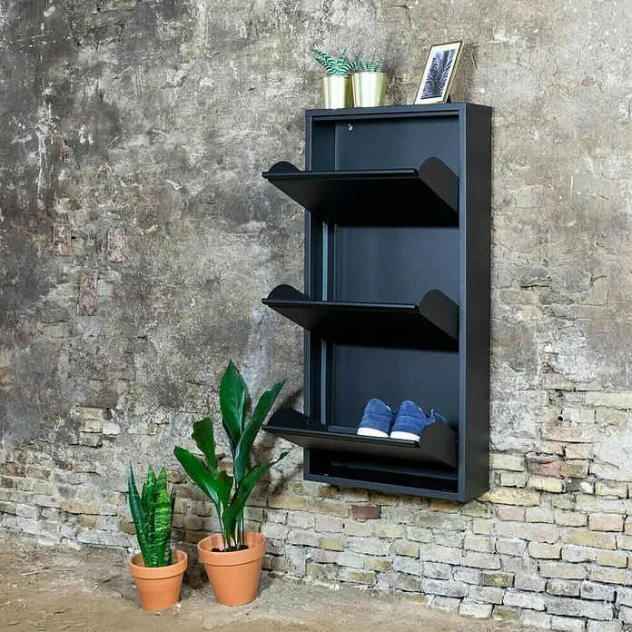 Spinder Design Schuhschrank Billy 3 - L x B x H: 15,5 x 50 x 103 cm, Schwarz - Schwarzer Schuhschrank mit drei Fächern an einer Wand montiert, dekoriert mit Pflanzen und einem Bild.