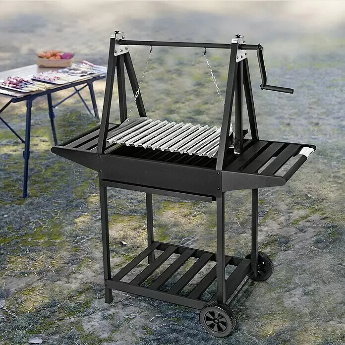 Grillstar Holzkohlegrill Idaho - Grillfläche (B x T): 58,6 x 39,5 cm, Schwarz - Schwarzer Metall-Grill mit verstellbarem V-Rost auf Rädern, im Freien mit Tisch im Hintergrund.