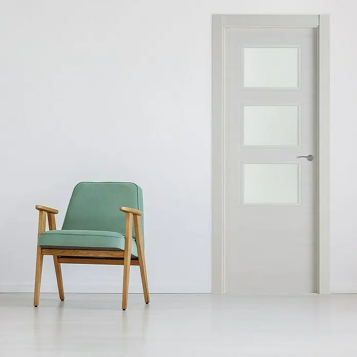 Pack puerta acristalada Nebraska - 82,5 x 203 cm, Izquierda, Gris claro - Interior con un sillón verde menta y una puerta moderna con tres inserciones rectangulares de vidrio, dando un toque elegante a la estancia.
