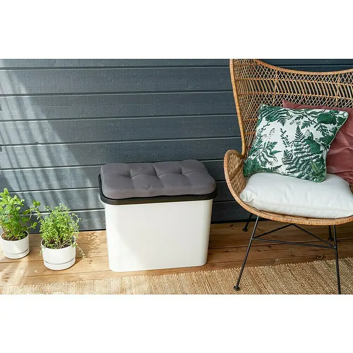SmartStore Collect Sitzkissen - L x B x H: 58 x 38 x 4,5 cm, SmartStore Mülltrennsystem Collect - Nahaufnahme einer weißen Aufbewahrungsbox mit grauem Kissen auf einer Holzterrasse mit einem Korbweidenstuhl und Pflanzen.