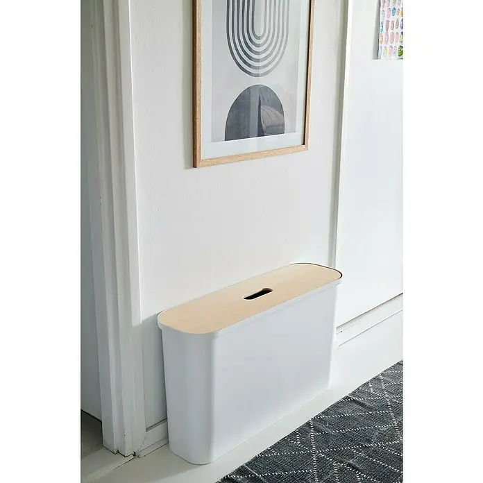 SmartStore Collect Mülltrennsystem Slim - 46 l, Weiß, Rechteckig, Kunststoff - Weißer Sitzhocker mit Holzplatte und Griffloch vor einer Wand mit Bildern und neben einer Tür, ideal für den Flur.