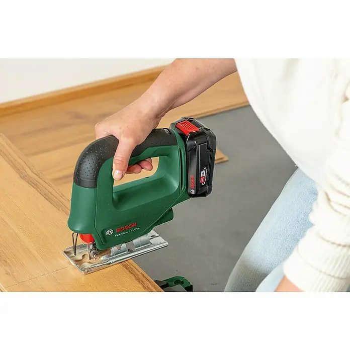 Bosch Power for All 18V Akku-Stichsäge EasySaw 18V-70 - 18 V, 1 Akku, 2 Ah, Leerlaufhubzahl: 2.600 /min - Nahaufnahme einer Person, die eine Bosch EasySaw 18V-70 Stichsäge zum Schneiden eines Holzstücks verwendet.