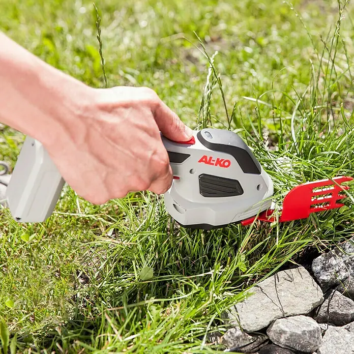 AL-KO Akku-Gras- & Strauchschere GS 7,2 Li - 7,2 V, Li-Ionen, 2 Ah, 1 Akku - Nahaufnahme einer Person, die eine AL-KO Akku-Grasschere benutzt, um Gras an einem sonnigen Tag zu schneiden.