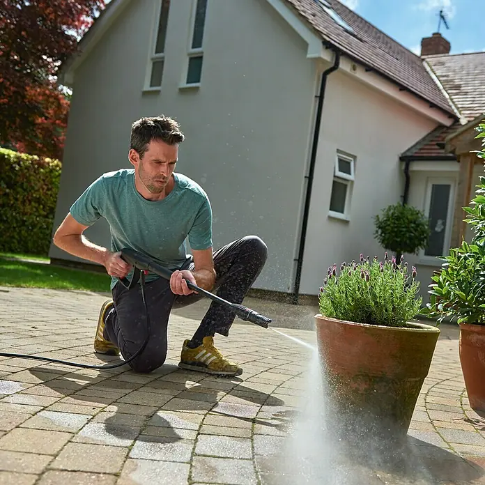 Bosch Hochdruckreiniger UniversalAquatak 130 - 1.700 W, Fördermenge: 380 l/h - Ein Mann reinigt mit einem Hochdruckreiniger einen Blumentopf, wodurch die Vielseitigkeit des Geräts für verschiedene Oberflächen hervorgehoben wird.