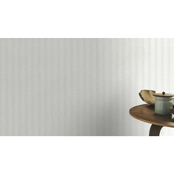 Rasch Wallton Vliestapete Fischgrät - Weiß, Streifen, 25 x 1,06 m - Ein elegantes Interieur mit einer strukturierten, hellgrauen Tapete und einem dekorativen Holztisch mit Keramikbehälter.