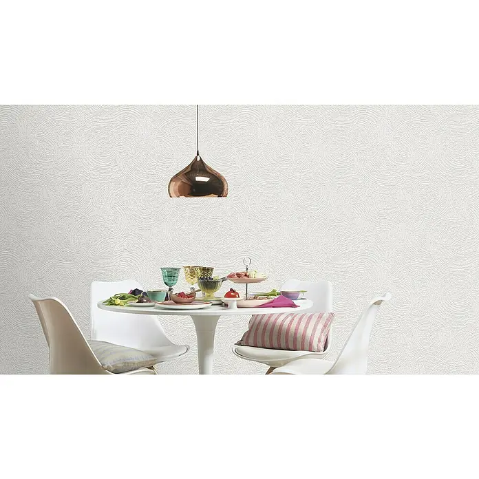 Rasch Wallton Vliestapete Premium Kreise - Weiß, Grafisch, 10,05 x 0,53 m - Ein Esstisch mit Geschirr und Stühlen unter einer kupferfarbenen Hängelampe vor einer strukturierten, weißen Wand sorgt für ein stilvolles Ambiente.