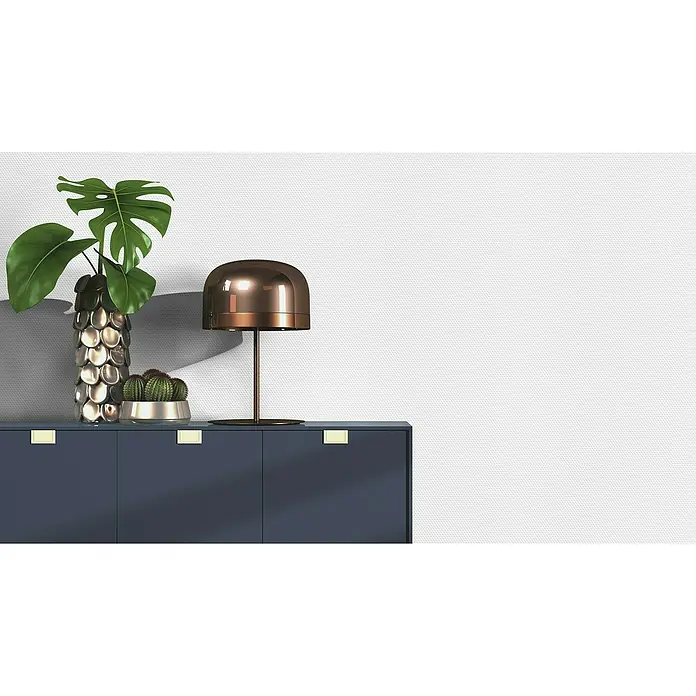 Rasch Vliestapete Feel Good Glasfaser-Optik - Weiß, Uni, 10,05 x 0,53 m, Wabenstruktur - Elegante Kommode in Dunkelblau mit goldenen Akzenten, dekoriert mit Lampe, Pflanze und Kaktus vor weißer Wand. Stilvolles Möbelstück.