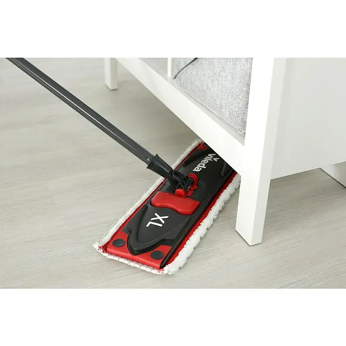 Vileda Ultramax Flachwischer XL System 2in1 - Materialspezifizierung: Mikrofaser - Nahaufnahme eines Vileda XL-Wischmopps unter einem weißen Möbelstück, der den Boden wischt und für Sauberkeit sorgt.