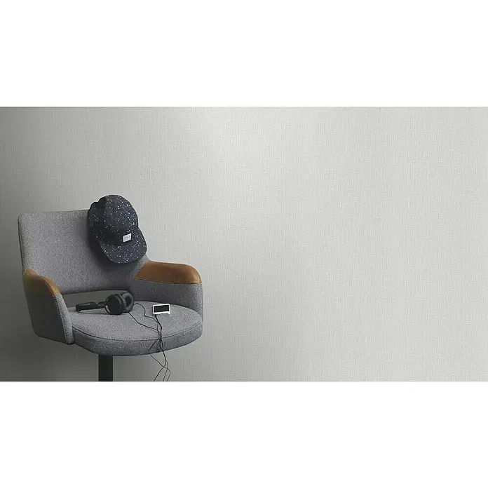 Rasch Wallton Vliestapete Grobe Leinenstruktur - Weiß, Uni, 25 x 1,06 m - Nahaufnahme eines grauen Stuhls mit einem Hut, Kopfhörern und einem Musikplayer darauf, vor einer neutralen Wand für Produktdarstellungen.
