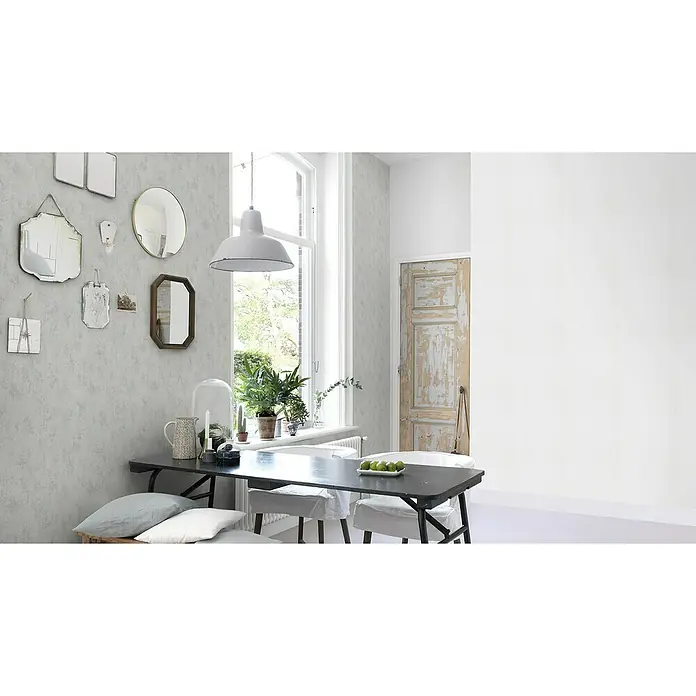 Rasch Wallton Vliestapete Premium Feine Putzstruktur - Weiß, Uni, 25 x 1,06 m - Eine stilvolle Essecke mit einem dunklen Tisch, umgeben von Stühlen und dekoriert mit Spiegeln an der Wand. Die helle Pendelleuchte setzt einen Akzent.