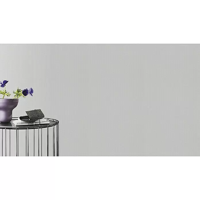 Rasch Wallton Vliestapete Premium Feine Putzstruktur - Weiß, Uni, 25 x 1,06 m - Runder Beistelltisch mit Chromgestell, schwarzer Platte, lila Vase mit blauen Blumen und zwei dunklen Perlenclutches auf Büchern.