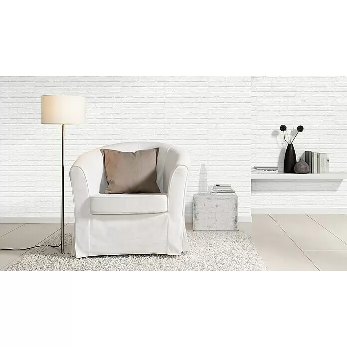 Rasch Wallton Vliestapete Mauersteine I - Weiß, Steinoptik, 10,05 x 0,53 m - Weißer Stoff-Sessel mit beigem Kissen auf einem weißen Hochflorteppich in einem hellen Raum.