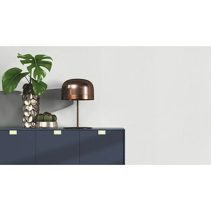 Rasch Wallton Vliestapete Gewebeoptik - Weiß, Uni, 10,05 x 0,53 m, Feine Struktur, Matt - Elegantes Sideboard in Marineblau mit goldenen Griffen, dekoriert mit einer Monstera-Pflanze, Kakteen und einer bronzefarbenen Lampe.