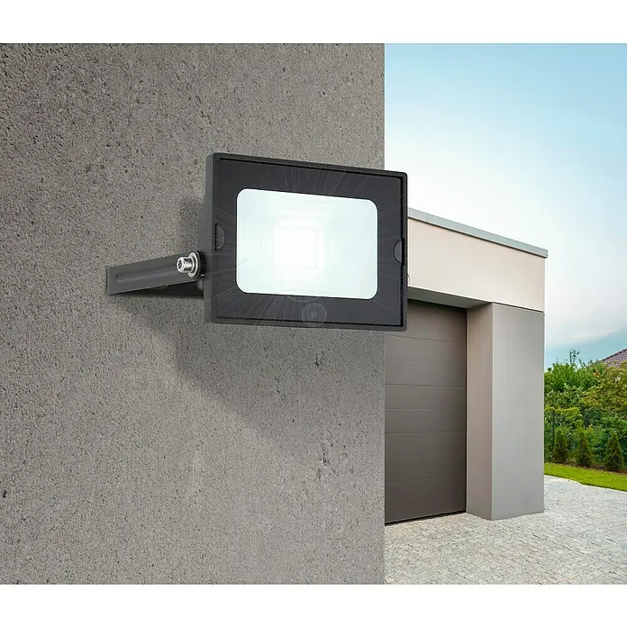 Globo LED-Strahler Helga - 10 W, Schwarz, Kaltweiß - Eine helle, rechteckige LED-Außenleuchte mit schwarzem Gehäuse ist an einer grauen Betonwand neben einer Garage montiert.