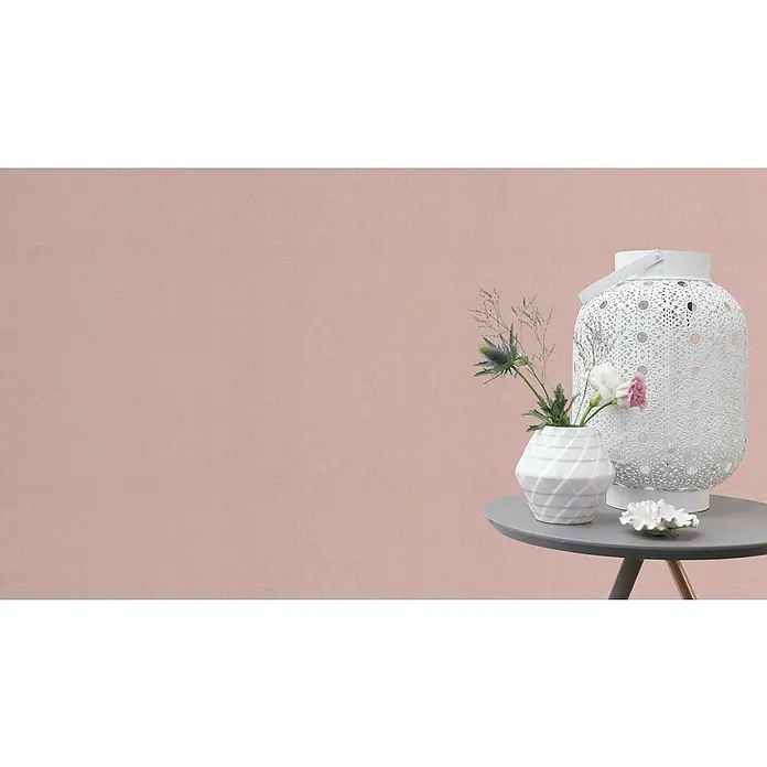 Rasch Bambino XIX Vliestapete - Rosa, Uni, 10,05 x 0,53 m - Nahaufnahme einer weißen Laterne und einer Vase mit Blumen auf einem grauen Tisch, die ein stilvolles und dekoratives Ambiente schaffen.
