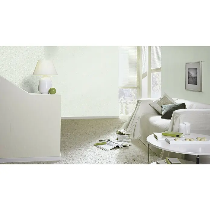 Rasch Bambino XIX Vliestapete - Salbei, Uni, 10,05 x 0,53 m - Helles Wohnzimmer mit einer weißen Couch, einem Couchtisch und einer Lampe, die eine entspannende Atmosphäre schafft.