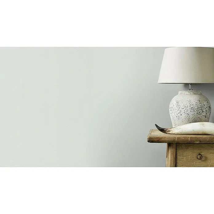 Rasch Salsa Vliestapete Textilstruktur - Mint, Uni, 10,05 x 0,53 m - Elegante Tischlampe mit Steinfuß und hellem Schirm auf einem rustikalen Holztisch, ergänzt durch ein dekoratives Horn.