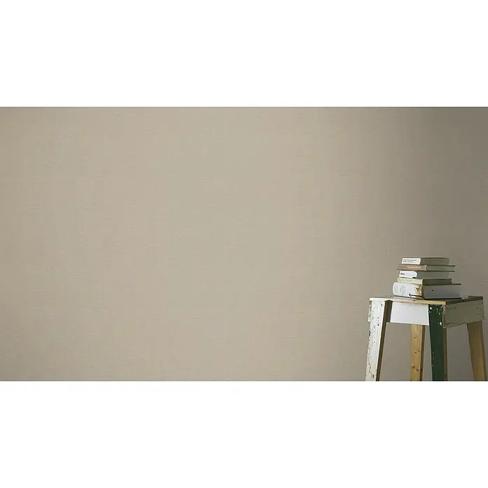 Rasch Salsa Vliestapete - Braun, Uni, 10,05 x 0,53 m - Detailaufnahme eines Stapels Bücher auf einem Beistelltisch vor einer schlichten Wand, die ein Gefühl von Ruhe und Intellekt vermittelt.