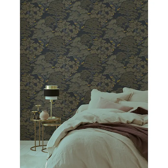 Rasch Salsa Vliestapete Bäume - Mattgold, Floral, 10,05 x 0,53 m - Schlafzimmer mit einer Wandtapete mit Waldmuster, einem Bett mit vielen Kissen und einem Nachttisch mit einer Lampe.