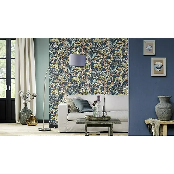Rasch Florentine III Vliestapete - Dunkelblau, Uni, 10,05 x 0,53 m - Elegantes Wohnzimmer mit tropischer Tapete, stilvoller Stehlampe und komfortablem Sofa, akzentuiert durch dekorative Elemente und sanfte Beleuchtung.
