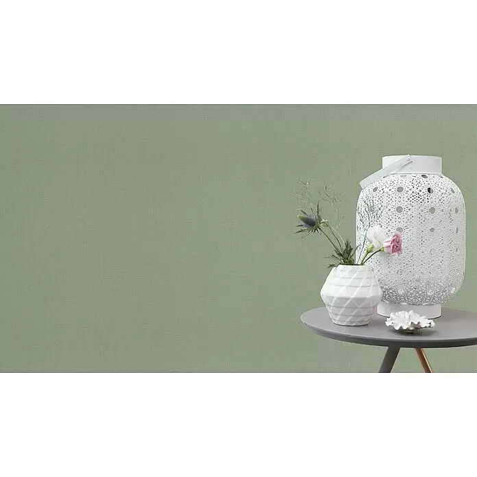 Rasch Florentine III Vliestapete - Salbei, Uni, 10,05 x 0,53 m - Grüne texturierte Wandverkleidung, dekoriert mit weißer Laterne, Vase und Muschelschale auf grauem Tisch.