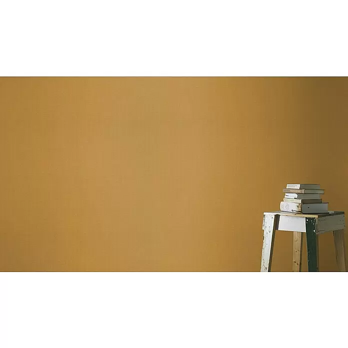 Rasch Florentine III Vliestapete - Cognac, Uni, 10,05 x 0,53 m - Senfgelbe strukturierte Wandverkleidung mit Büchern auf einem rustikalen Holzschemel.