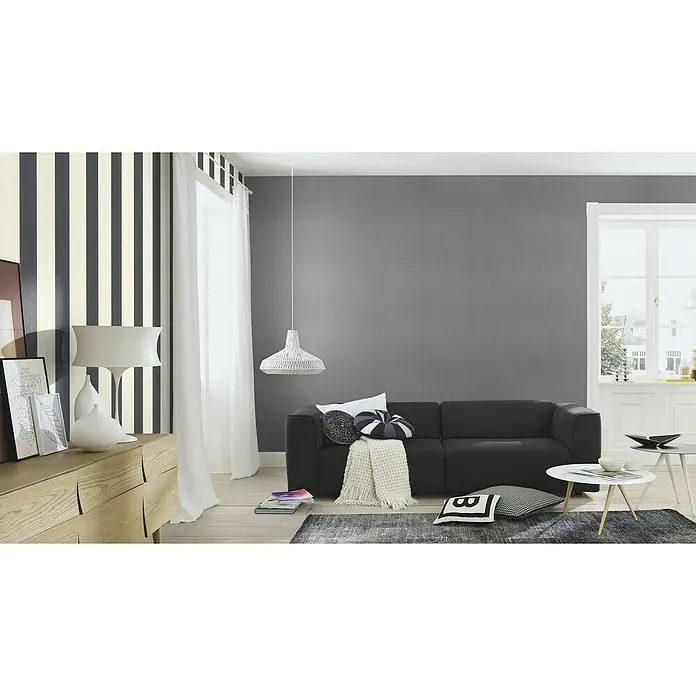 Rasch Florentine III Vliestapete - Weiß-Anthrazit, Streifen, 10,05 x 0,53 m - Einrichtungsidee mit einem grauen Sofa, einem weißen Lampenschirm und einem hellen Holzschrank, die ein modernes und stilvolles Ambiente schaffen.